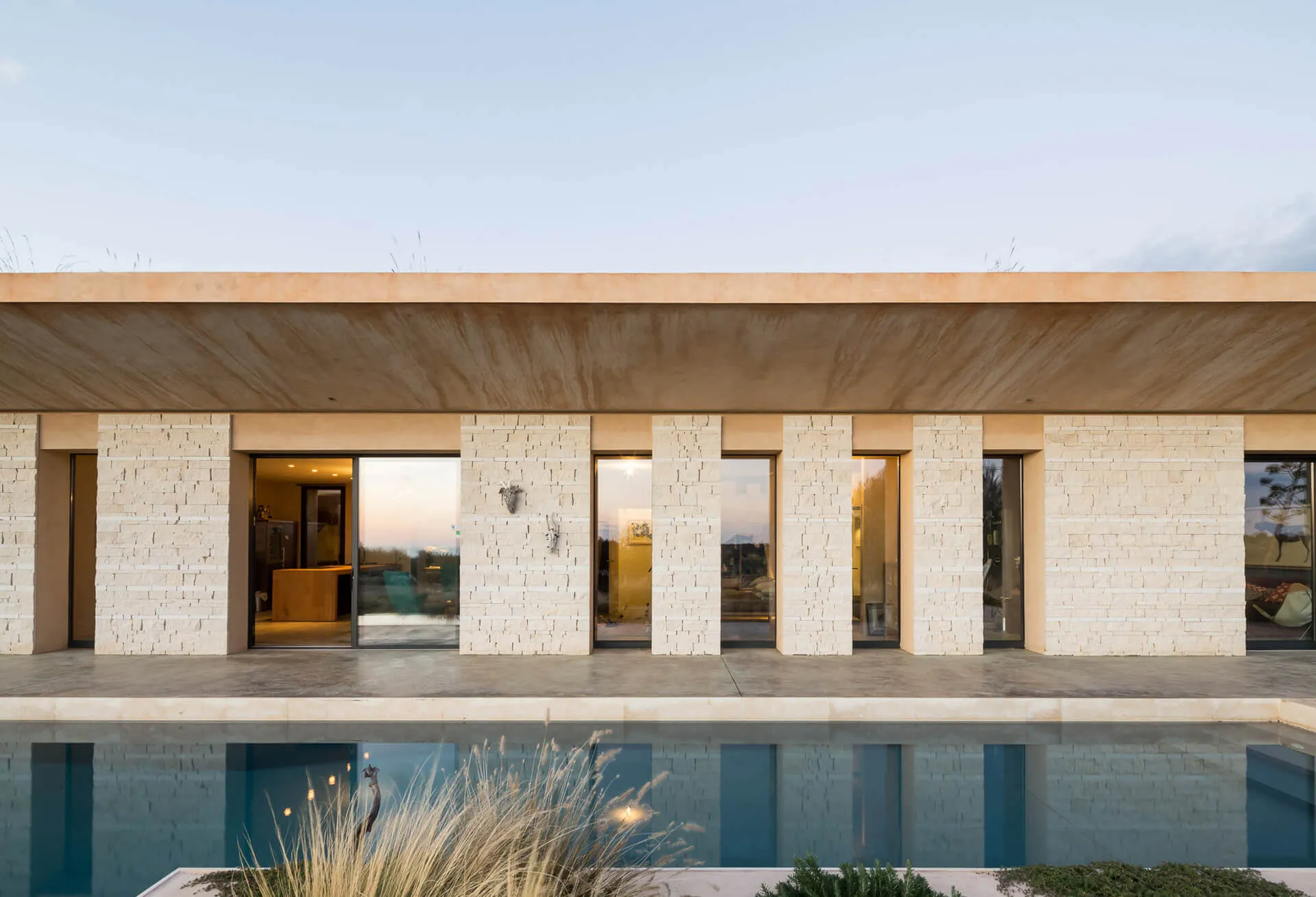 Fotografia dell'esterno della casa Casa ECS, con muro esterno beige, porte finestre e piscina esterna.