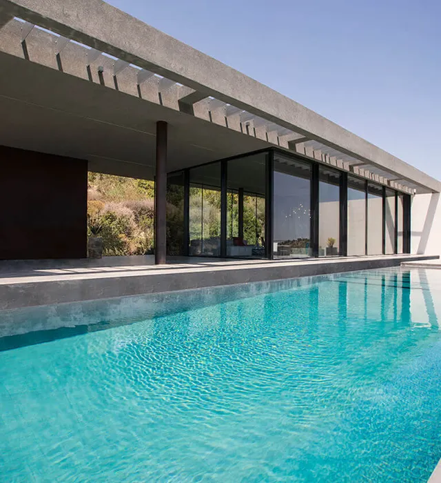 Fotografia dell'esterno della Casa Orizzonte, con un design raffinato e porte integrate, vista piscina esterna e porte finestre per tutta la lunghezza della piscina.