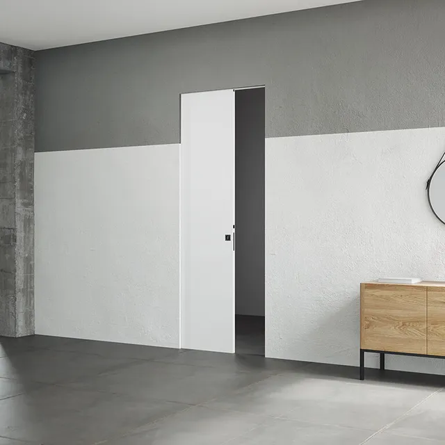 Porta scorrevole progettata per scomparire nella parete, ottimizzando lo spazio e aggiungendo un tocco contemporaneo all'ambiente. La porta è di colore bianco e si immedesima bene nel muro che è per metà bianco (la parte sotto) e per metà grigio topo (la parte sopra).