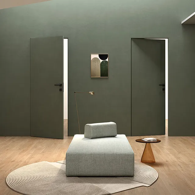 Doppia porta battente filo muro reversibile su stessa parete. La porta a sinistra si apre verso di noi, la porta a destra si apre verso l'esterno. L'ambiente è moderno e la parete di riferimento comprese le porte è di colore verdone scuro tendente al grigio.